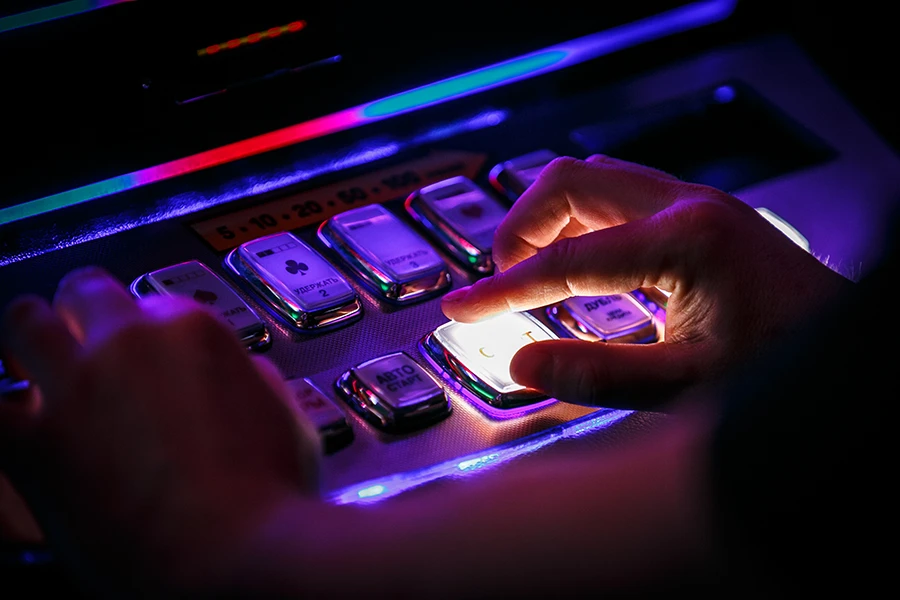 close up shot of a hand pressing the play button on a slot machine